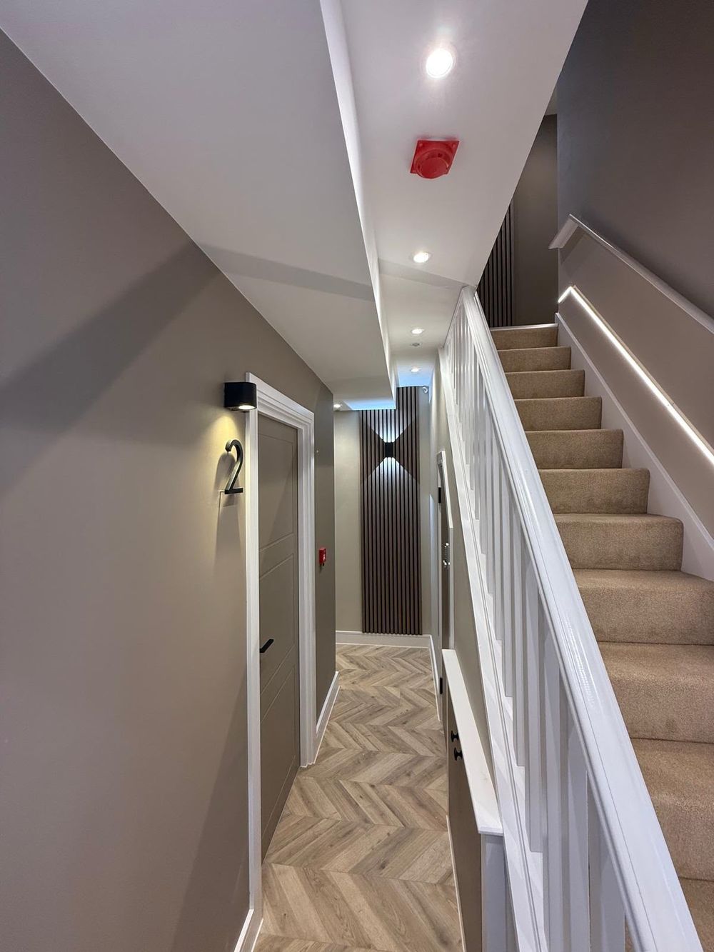Finished hallway and staircase with plasterboard bulkhead and downlights after a residential loft conversion