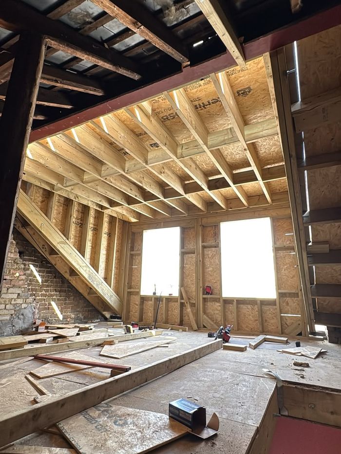 New loft roof structure with timber joists and window openings ready for insulation and boarding